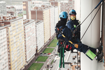 Industry mountaineer laborers hangs over residential house facade. Two workers in uniform and...