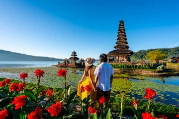 Fototapeten Bali Young couple tourist relaxing and enjoying the beautiful view at Ulun Danu Beratan temple in Bali, Indonesia  © Kittiphan