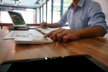 Businessman analyzing investment charts and pressing calculator buttons over documents. Accounting Concept