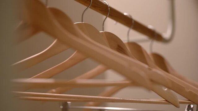 Empty wooden clothing hangers hanging on metal rack close up view. Shopping and discount concept.