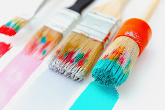 Creative background of artist tassels or brushes in bright paint, mixed paints, vivid art brushes, close up