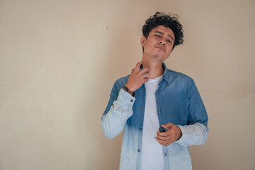 Young curly man with denim clothes wear perfume. Smile, cheers and happy expression. The photo is...