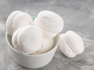 Marshmallows in bowl on a gray background. Sweet dessert zephyr marshmallows on concrete. Close up