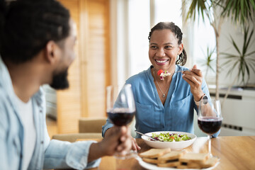 Happy black couple talking to each other while having a meal at dining table