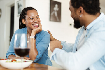 Happy African American couple talking while enjoying in lunch time at home
