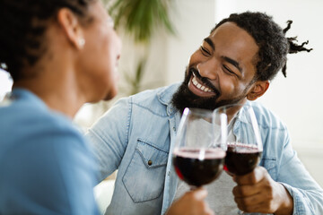 Happy African American couple toasting with wine at home