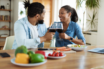 Happy African American couple toasting with wine during lunch at dining table