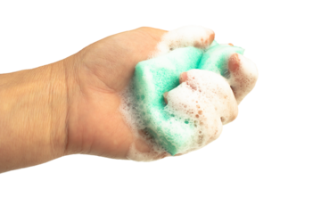 A woman's hand holds a green sponge with soapy foam isolated on a transparent background.