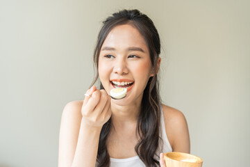 Protein in food, happy smiling asian young woman, girl in diet eat boiled egg, hand holding spoon...