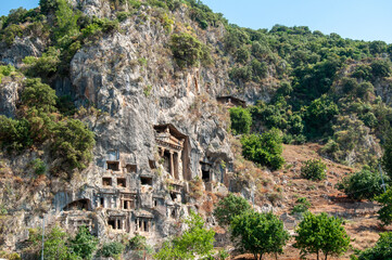 Amyntas rock tombs - 4th BC tombs carved in steep cliff. Tourist stands in front of the door. City of Fethiye, Turkey.