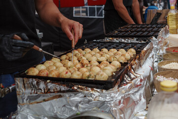 Selective focus at Takoyaki, ball-shaped Japanese snack made of a wheat flour-based batter and...