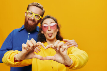 Man and woman couple smiling cheerfully and crooked with glasses, on yellow background, symbols signs and hand gestures, family shoot, newlyweds.