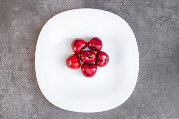Red cherries on a white plate. Delicious dessert, juicy berries, top view