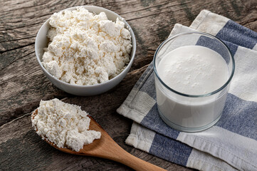 Cottage cheese in a bowl and Kefir, buttermilk or yogurt glass on Rustic wooden table background. Organic healthy food. Farm dairy products