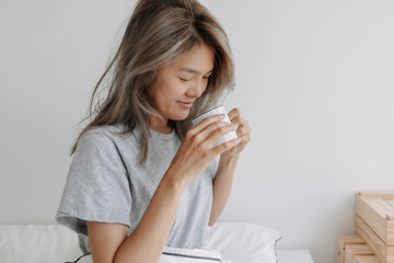 Asian woman drink coffee in the morning on the bed. High quality photo
