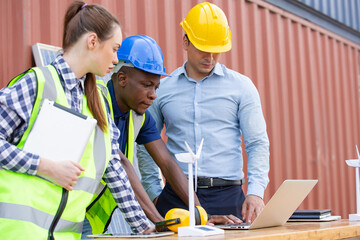 Engineer worker team discussing of solar energy from wind turbine model and laptop at construction site. diversity people brainstorming and working together