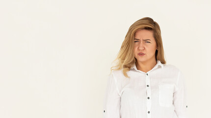 Studio shot of cute girl with fair hair and confused face isolated on white background