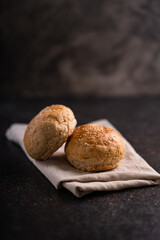 Fresh whole grain brown buns with sesame seeds on rustic background. Healthy artisan bread.