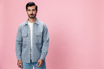 Obraz premium Portrait of a stylish brunette man with a beard beautiful smile on a pink background in a white T-shirt and jeans smile and joyful emotion on his face, copy space