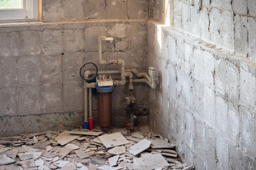 Renovation in an old room, dismantled floor tiles, concrete walls, plumbing elements, construction...
