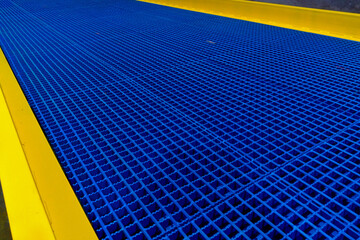 The flooring of the mobile overpass is made of steel lattice in blue and yellow tones.