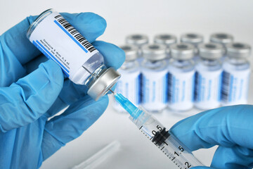 Medical personnel filling a syringe needle with generic vaccine booster from vial with blank label - mock up copy space  - obrazy, fototapety, plakaty