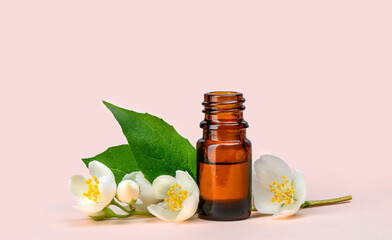 White jasmine flowers with green leaves and cosmetic brown glass bottle
