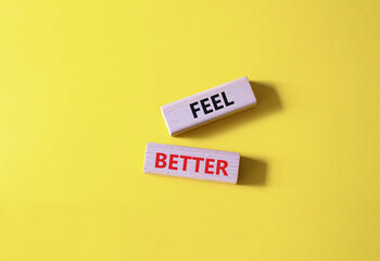 Feel better symbol. Wooden blocks with words Feel better. Beautiful yellow background. Business and Feel better concept. Copy space.