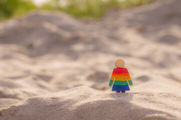 LGBT wooden people on the beach on the sand. Couple standing on beach with rainbow flag, equal rights, symbol of LGBT community. LGBT flag on a sandy beach. Summer travel concept. A symbol of same-sex