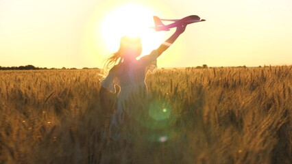 little child girl daughter runs through wheat field with toy plane her hand sunset, happy family dream fly, kid child with airplane, holiday child runs with toy plane across field rays sunset summer