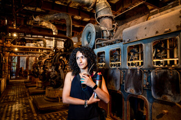 Portrait of a mixed race woman smiling while posing inside an abandoned factory.