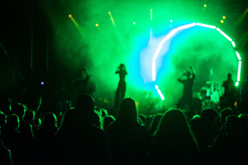 crowd at concert and silhouettes in stage lights .silhouettes of concert crowd in front of bright stage lights . cheering crowd in front of bright stage lights