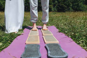 A woman is standing on a sadhu board. Close-up of legs .yoga nails in nature.