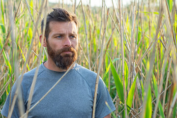 Serious looking young adult sitting in reed