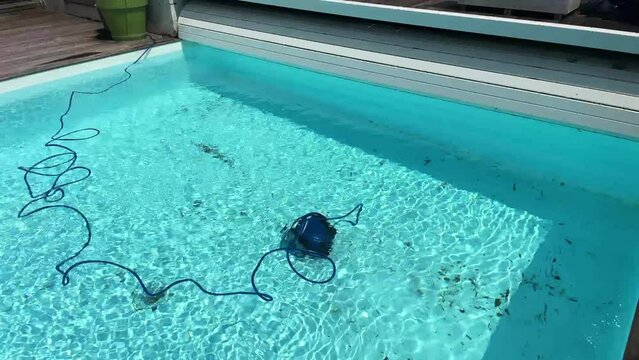 Underwater pool vacuum cleaner. Robotic cleaning of the pool floor. Pool cleaner robot Pool maintenance with automatic robot. Cleaning the bottom  and walls with a submersible robot.