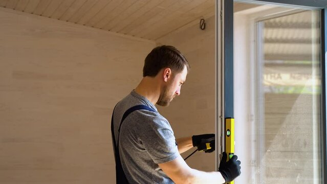 Worker measures of the vertical deviation of pvc windows in wooden prefabricated house