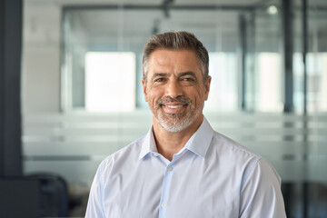 Happy mid aged older business man executive standing in office. Smiling 50 year old mature confident professional manager, confident businessman investor looking at camera, headshot close up portrait. - obrazy, fototapety, plakaty