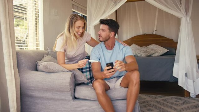 Excited couple in bedroom at home celebrating positive pregnancy test result - shot in slow motion