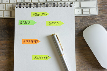 On a wooden table is a keyboard and mouse, a pen with a notepad with stickers with inscriptions on it.