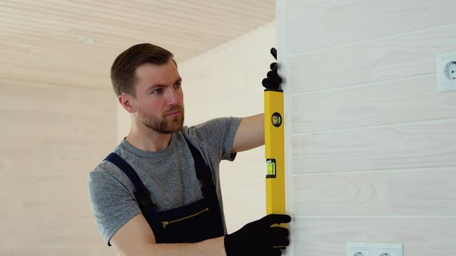 Builder measures of the vertical deviation of the wall in new wooden hotel room