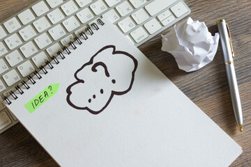 The concept of the idea is sketched in a notebook. The keyboard and mouse are on a wooden table.