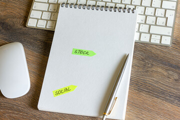 On a wooden table is a keyboard and mouse, a pen with a notepad with stickers with inscriptions on it.