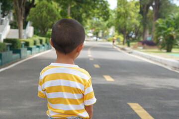 Obraz premium A boy looking at the road in the garden