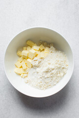 cubes of butter and sugar in a white bowl, organic butter  and granulated sugar about to be creamed in a white mixing bowl, process of making cake