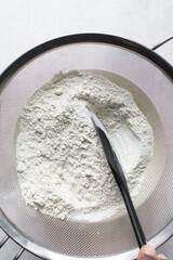 Sifting flour for baking, a silver sieve with flour in it