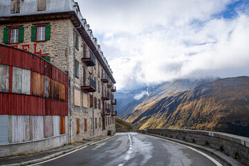 Mountain road in the Swiss Alps with old houses in the foreground