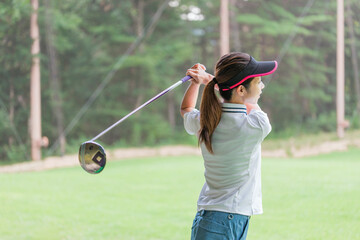 ゴルフ練習場・打ちっぱなし・ゴルフセンターでスイングの練習するゴルフ選手・ゴルファーの女性
