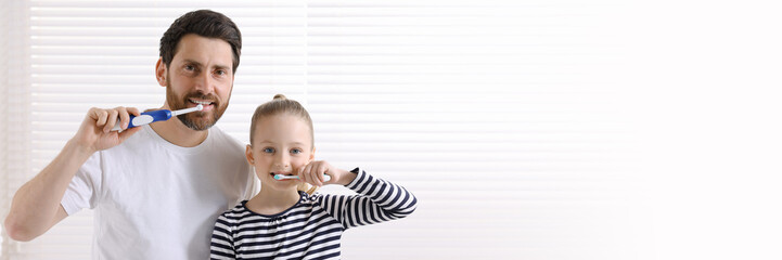 Father and his daughter brushing teeth together indoors. Banner design with space for text