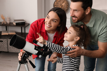 Happy family using telescope to look at stars in room