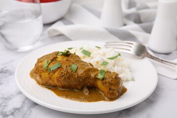Delicious rice and chicken with curry sauce served on white marble table, closeup